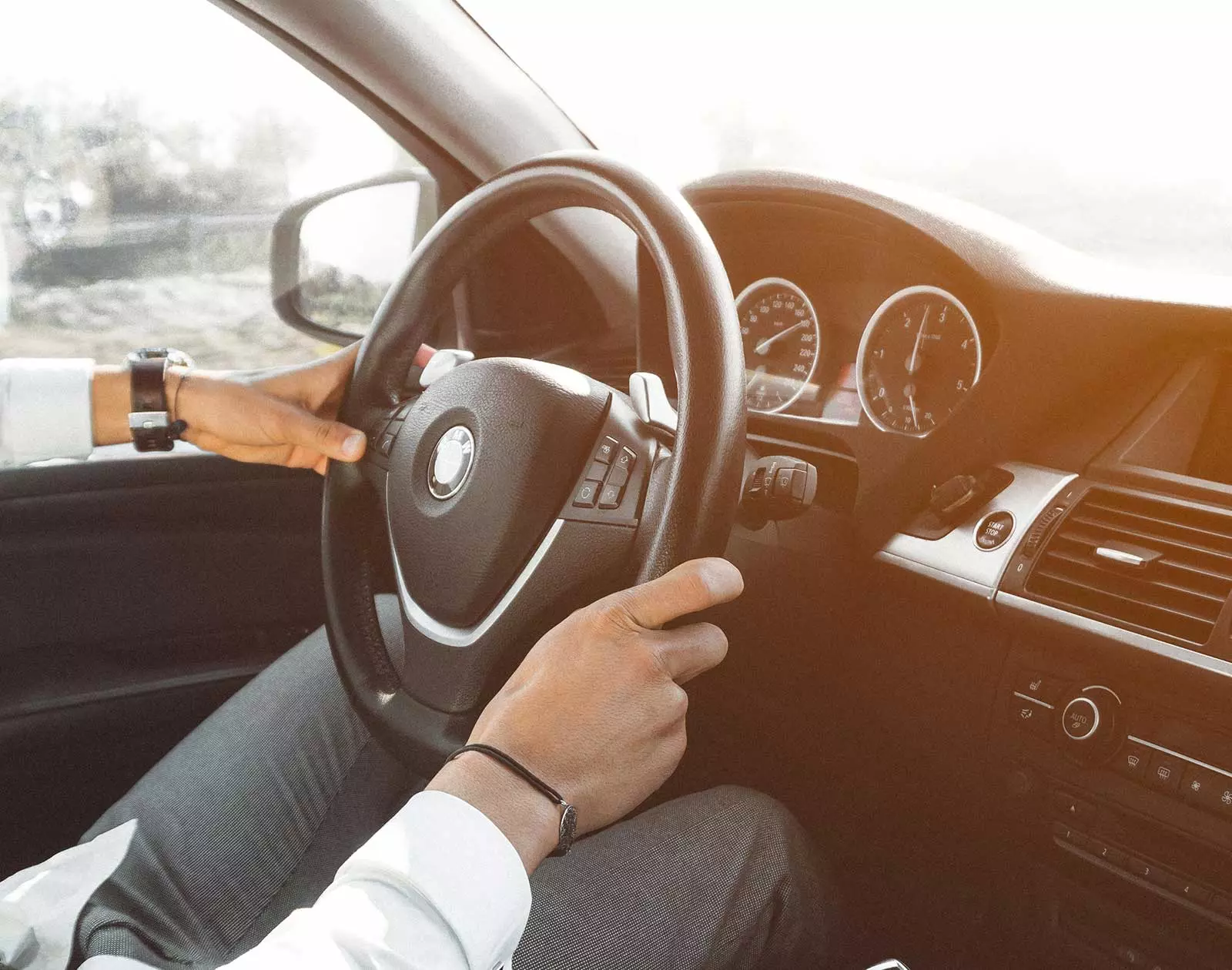 Ansicht einer Person mit Händen am Lenkrad eines BMW-Cockpits